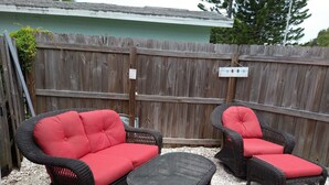 Ein Patio mit Korbmöbeln, darunter zwei Stühle und ein Sofa, sowie ein kleiner Tisch.