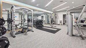 A modern gym with various exercise equipment, including weight machines and free weights, and a mirror wall for reflection. - "Faith of Evanston" 180°view, 2BDR +2Bath Urban luxury (Evanston)
