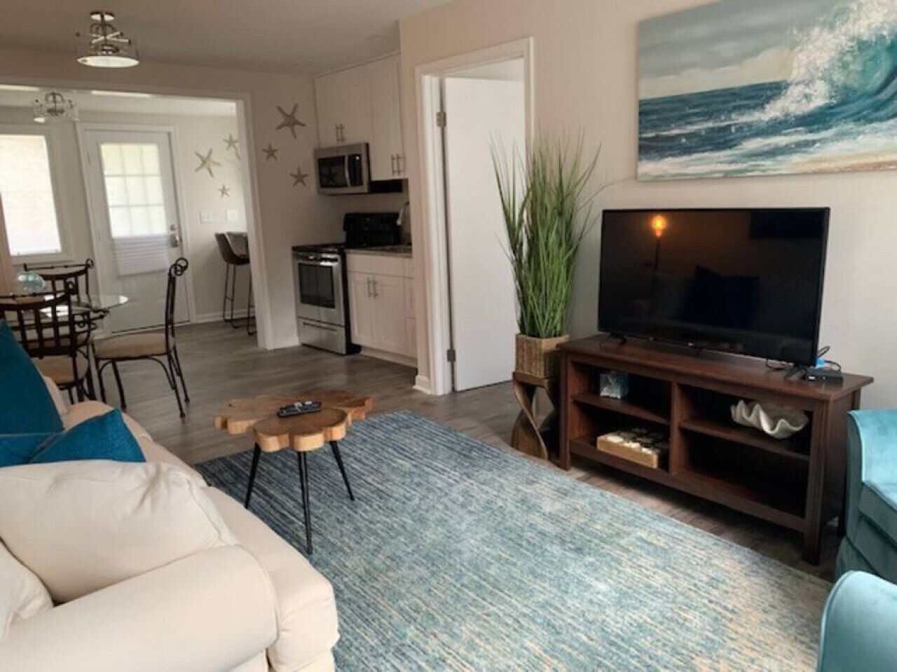 A living room with a sofa, coffee table, TV stand, and a plant.