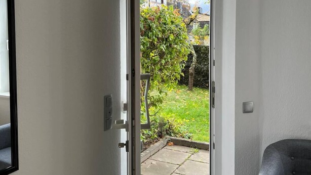 A room with a sliding glass door leading to a garden. - Gartenparadies Apartment  in Urbar (Urbar)