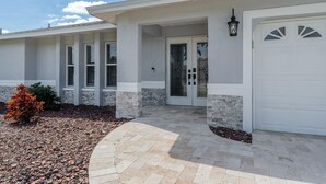A modern house with a stone facade, a white garage door, and a stone pathway leading to the entrance.
