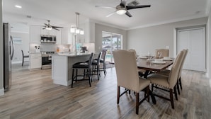 A modern kitchen with white cabinets, a central island, and a dining area with a table and chairs.