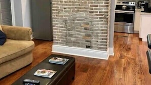 Ein Wohnzimmer mit Backsteinwand, einem gerahmten Bild, einer Couch und einem Couchtisch.