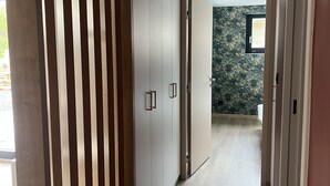 A hallway with a wooden slat partition, a sliding door, and a view into a room with a window.