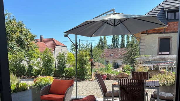 An outdoor patio area with wicker furniture, a table, and an umbrella.