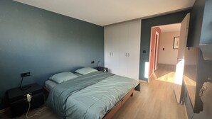 A bedroom with a bed, nightstands, a dresser, and a wardrobe.