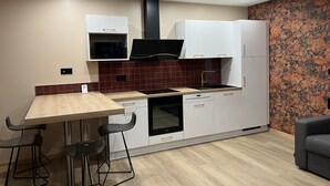 A modern kitchen with a wooden table, bar stools, a built-in oven, and white cabinets.