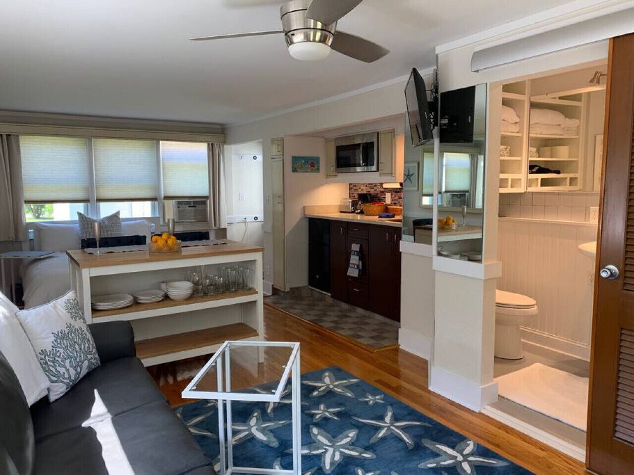 Un espace de vie compact comprenant une kitchenette, un coin repas et une salle de bain.