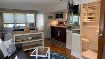 Un espace de vie compact comprenant une kitchenette, un coin repas et une salle de bain.