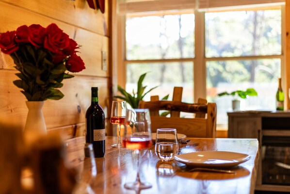 A wooden table with a bottle of wine, a glass, and a vase of red roses. - Heavenly Bliss By Ghosal Luxury Lodging (Sevierville)