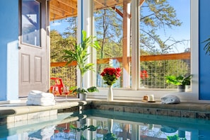 A pool area with a clear view of the surrounding landscape, a wooden deck, and a window with a view of trees.