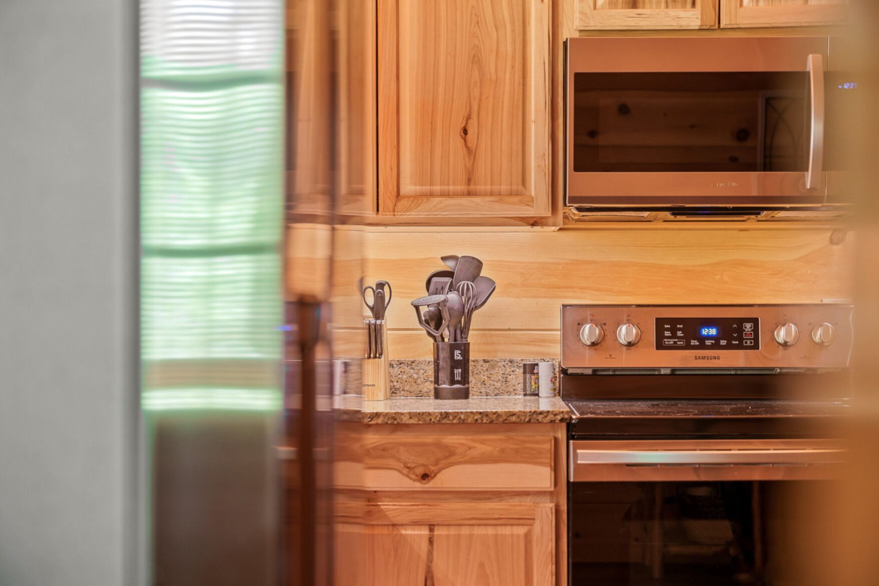 A kitchen with wooden cabinets, a microwave, and a Samsung oven.