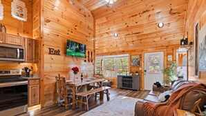 Interior de una cabaña de madera con cocina, comedor y sala de estar.