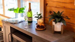 Una mesa de madera con una botella de vino, dos copas, una vela y plantas en macetas.