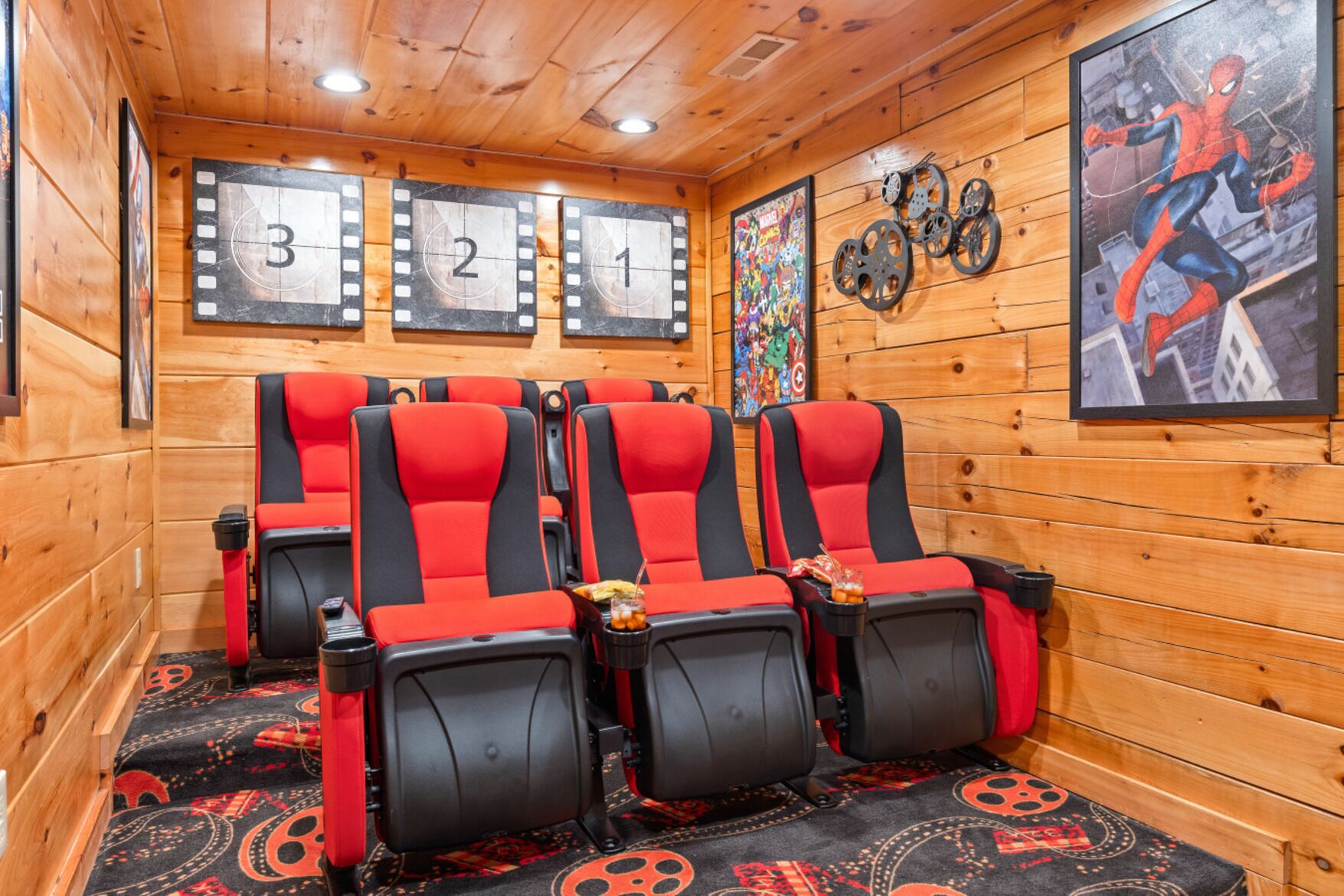 Een bioscoopzaal met rode en zwarte stoelen, een decoratieve filmstrip aan de muur, en een Spider-Man poster.