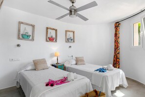 A hotel room with two beds, a ceiling fan, and framed pictures on the wall.