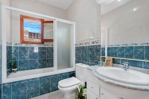 A bathroom with a toilet, sink, and window.