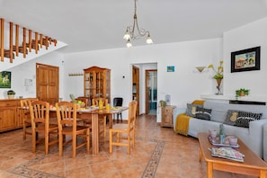 A spacious living room with a dining area, a staircase, and a kitchen.