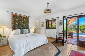 Camera da letto con un letto, due lampade sui comodini, una finestra con vista e una porta che dà su uno spazio all'aperto.