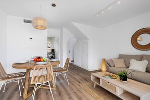Un espacio habitable moderno con comedor, sofá y cocina al fondo.