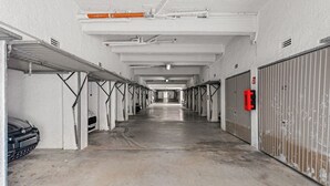 Un estacionamiento largo y vacío con múltiples filas de coches aparcados y puertas de garaje.