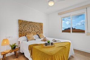 Un dormitorio con cama, mesita de noche, lámpara y ventana con vistas.