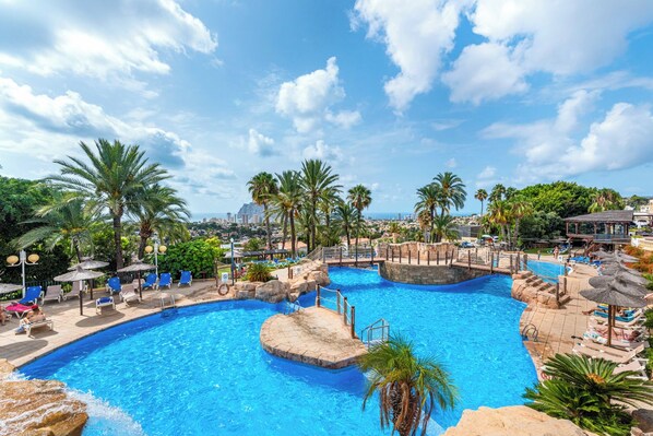 A large outdoor swimming pool with multiple lanes, surrounded by palm trees and lounge chairs.