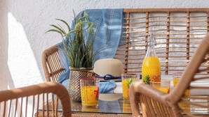 Une table en osier avec des chaises, une plante en pot et une bouteille en verre.