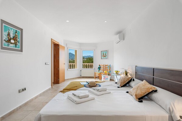 A bedroom with a bed, a window, a door, and a view of the outdoors.
