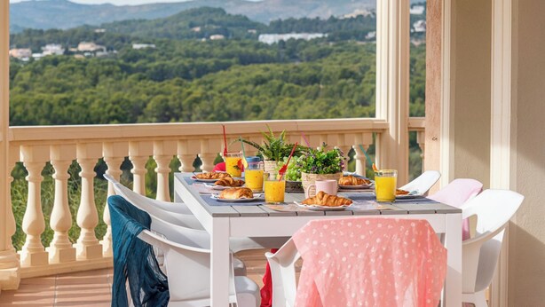 A balcony with a table set for breakfast, overlooking a mountainous landscape. - Villa Esperanza - PlusHoliddays (Calpe)
