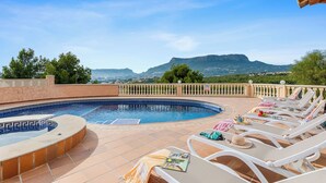 A pool area with lounge chairs and a view of mountains. - Villa Esperanza - PlusHoliddays (Calpe)
