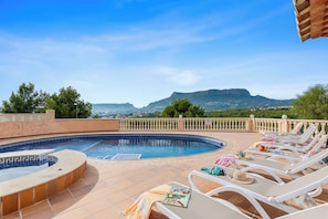 Area piscina con lettini e vista sulle montagne.