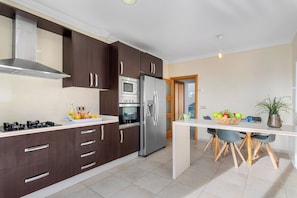 Una cucina moderna con mobili in legno scuro, elettrodomestici in acciaio inossidabile e un piano di lavoro bianco.