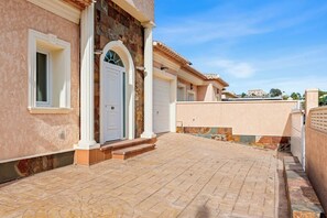 Un edificio con ingresso lastricato, una porta bianca e facciata in pietra.