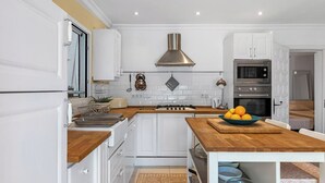 A modern kitchen with white cabinetry, a wooden countertop, a gas stove, and a stainless steel range hood. - Villa Domingo - PlusHolidays (Benissa)