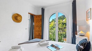 A bedroom with a bed, a window with curtains, a door, and a view of greenery outside. - Villa Domingo - PlusHolidays (Benissa)