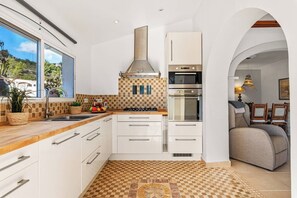 Une cuisine moderne avec des meubles blancs, une cuisinière à gaz et un four encastré.