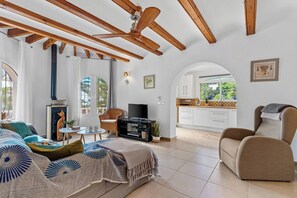 Un salon doté d’une cheminée, d’un téléviseur et d’un coin repas, avec une cuisine visible à travers une arche.