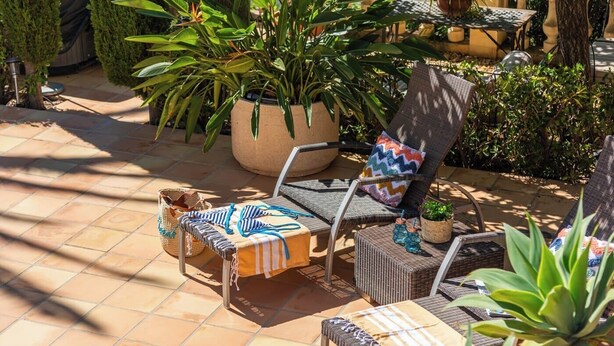 An outdoor seating area with lounge chairs, a table, and potted plants. - Villa Domingo - PlusHolidays (Benissa)