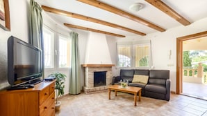 Un salon avec une cheminée, un canapé, un téléviseur et un meuble en bois.