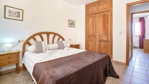 Une chambre à coucher comprenant un lit, une armoire en bois, des tables de chevet et une petite table de nuit.