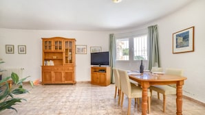Un coin repas avec une table et des chaises en bois, un téléviseur et un meuble avec des portes en verre.