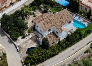 A two-story building with a tiled roof, a swimming pool, and a garden area.