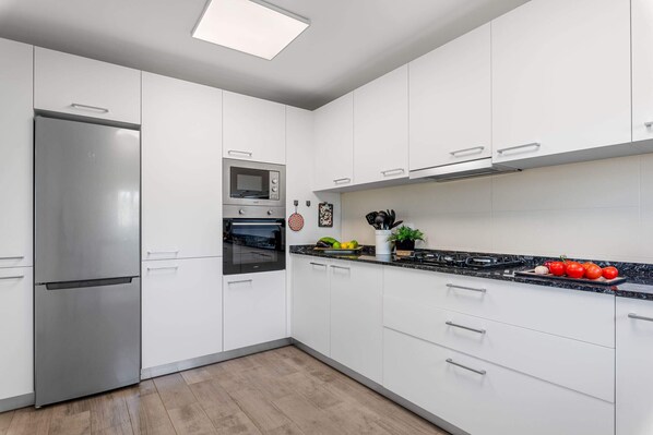 A modern kitchen with white cabinets, stainless steel appliances, and a granite countertop.