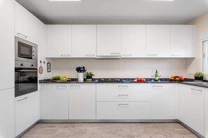 A modern kitchen with white cabinets, a built-in oven, and a granite countertop. - Villa San Marcos - PlusHolidays (Calpe)