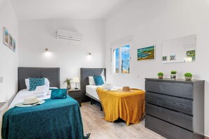 Quarto de hotel com duas camas, uma escrivaninha, um armário e obras de arte nas paredes.