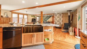 A spacious kitchen with wooden beams, a built-in dishwasher, and a large island with a sink.