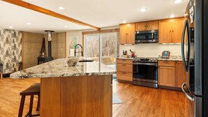 A modern kitchen with wooden cabinets, a large island, and stainless steel appliances.