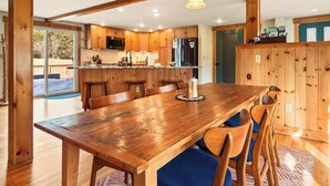 A spacious kitchen with wooden cabinets, a large wooden dining table, and a view to the outdoors.