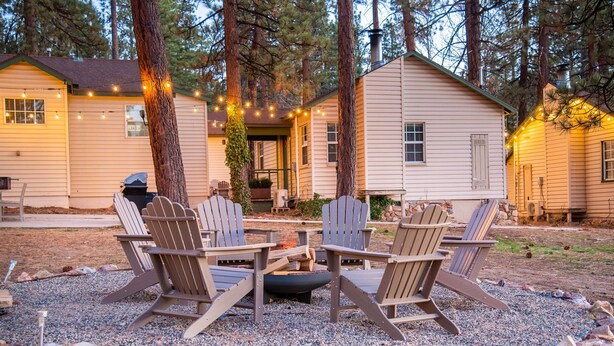 A cabin with a fire pit and Adirondack chairs in the yard.